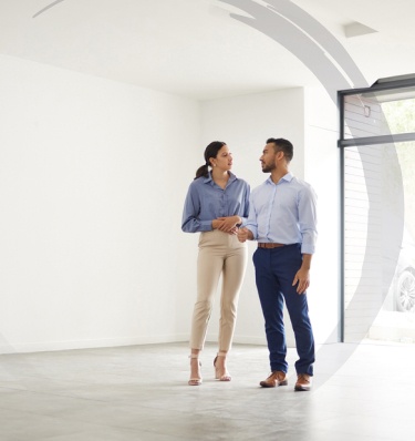 a young couple stand in their new, large apartment