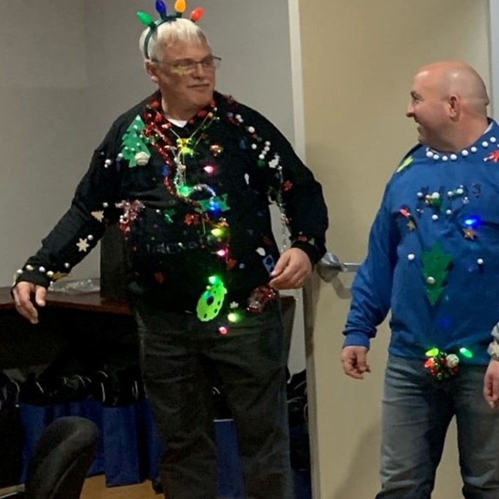 two men in tacky Christmas sweaters at holiday party