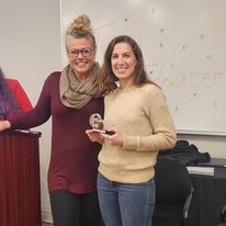 2 women posing for a picture with an award